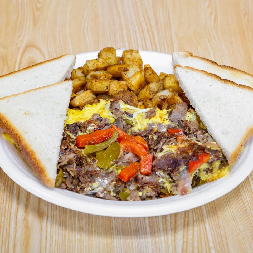 Hearty breakfast plate with scrambled eggs, steak, peppers, home fries, and white toast.